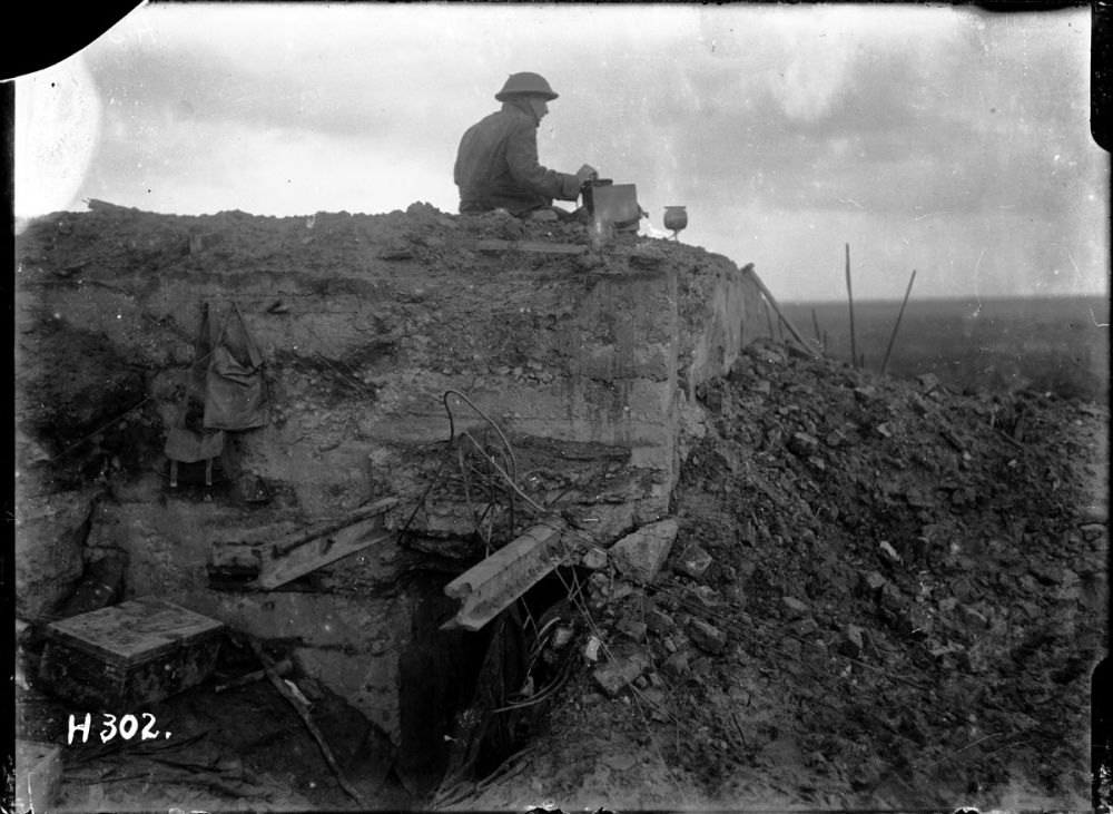 A New Zealand signaller operates on a destroyed German bunker at Gallipoli Farm, Belgium, 12 October 1917.